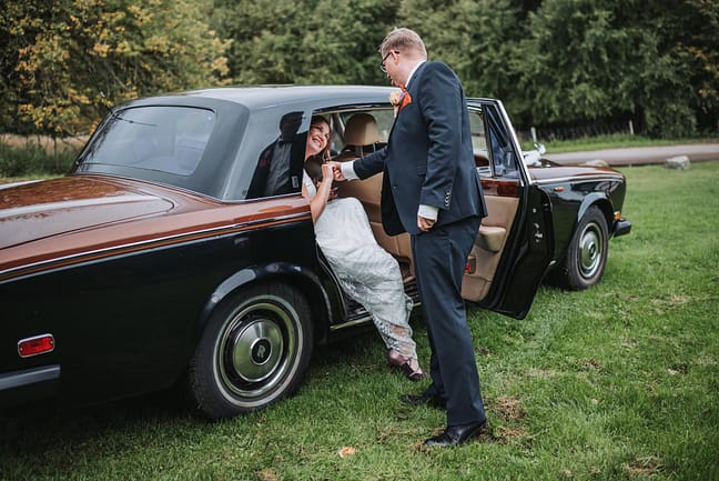 En gom der hjælper sin smukke brud ind i en Rolls Royce ved Tvis Mølle